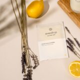 a wooden cutting board topped with a lemon next to a bottle of lotion