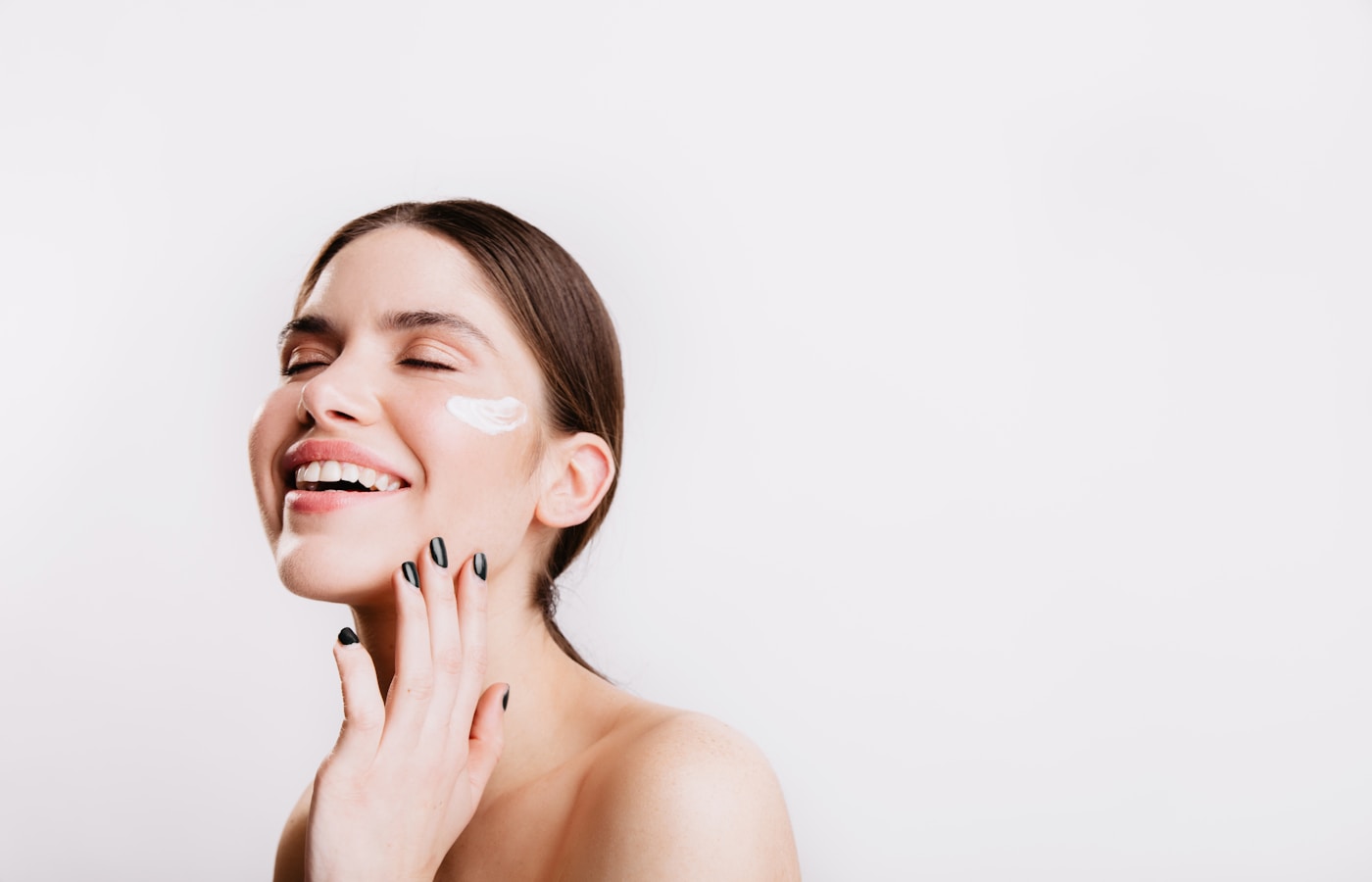 A woman smiles while she holds her hand to her face