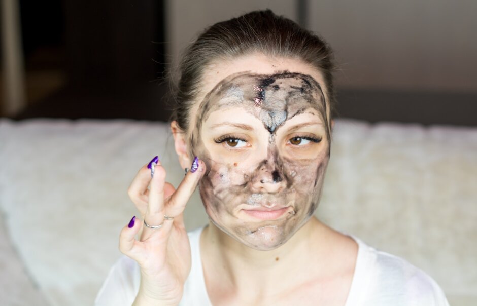 a woman with a face mask on holding her hand up to her face
