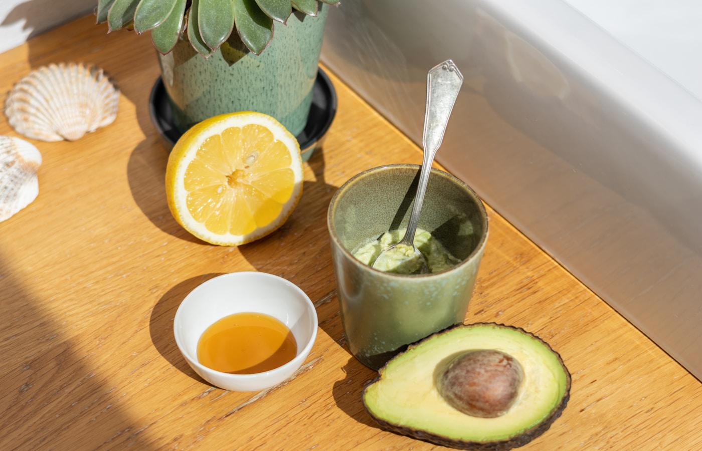 An avocado, lemon, and other ingredients are on a table